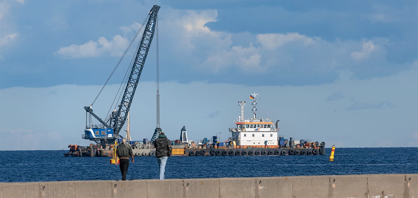 Ein Bagger hebt auf offener See einen Tunnelgraben aus