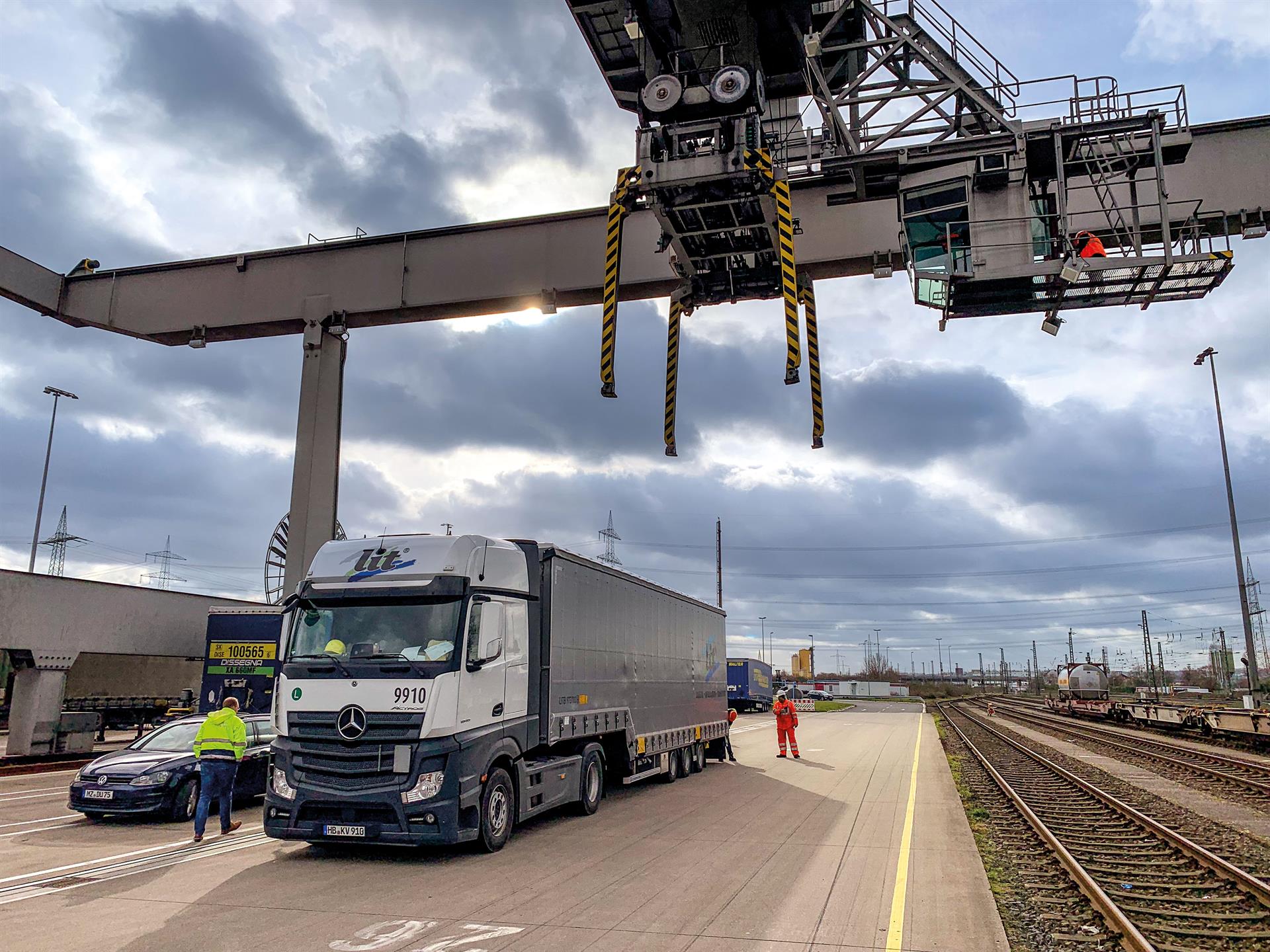 Ein Kran eines Güterzugs belädt einen LKW mit einem Container.