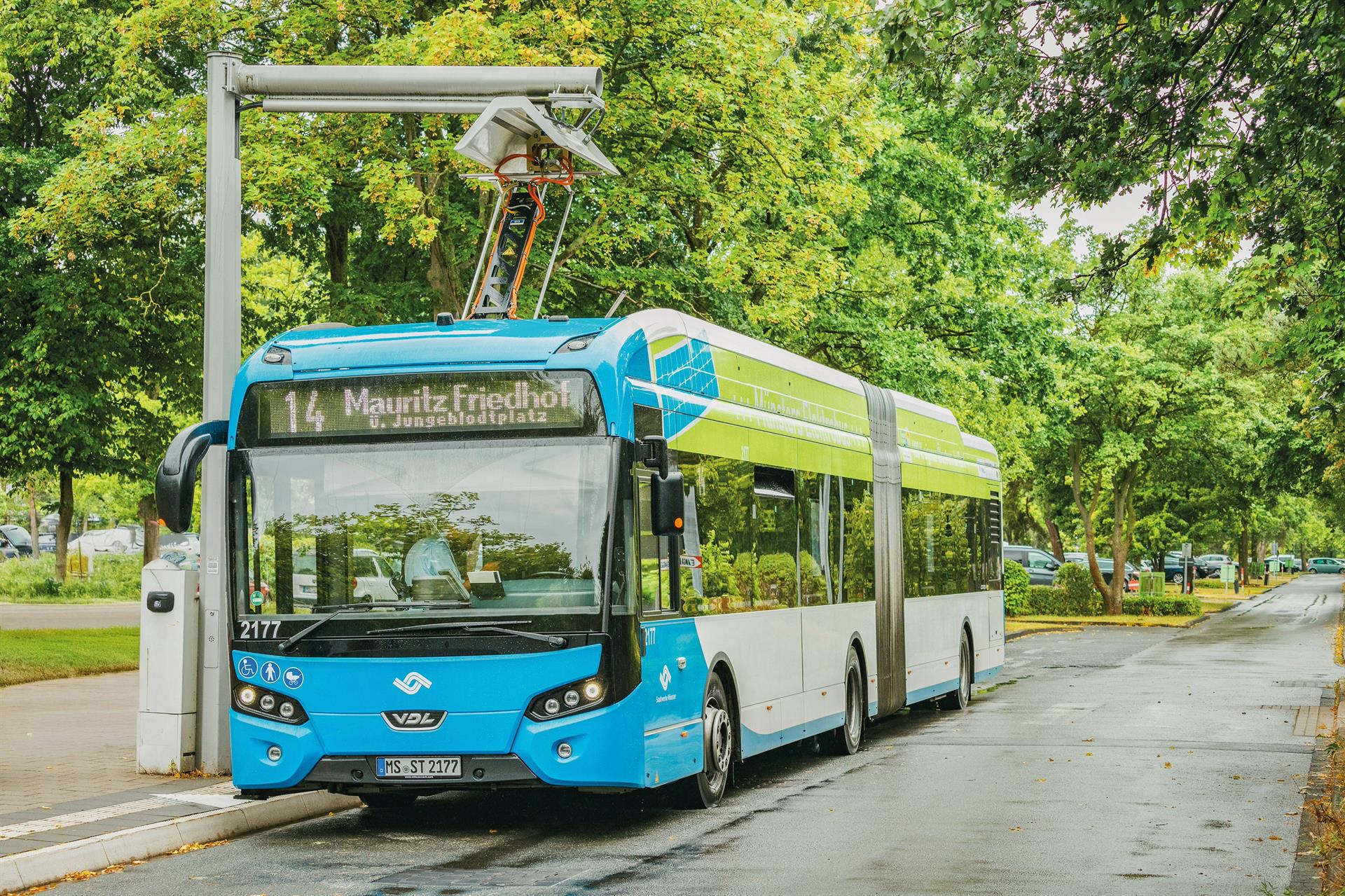 Moderner Elektrobus mit Stromabnehmer lädt an einem Oberleitungsmast.